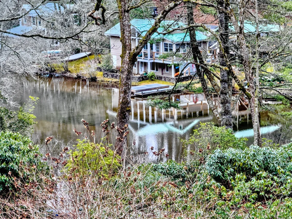A tranquil lakefront scene with a house by the water and a private dock extending out over the still surface. The setting is serene, with reflections in the water and hints of activities like fishing or boating, illustrating the lakeside playground described.