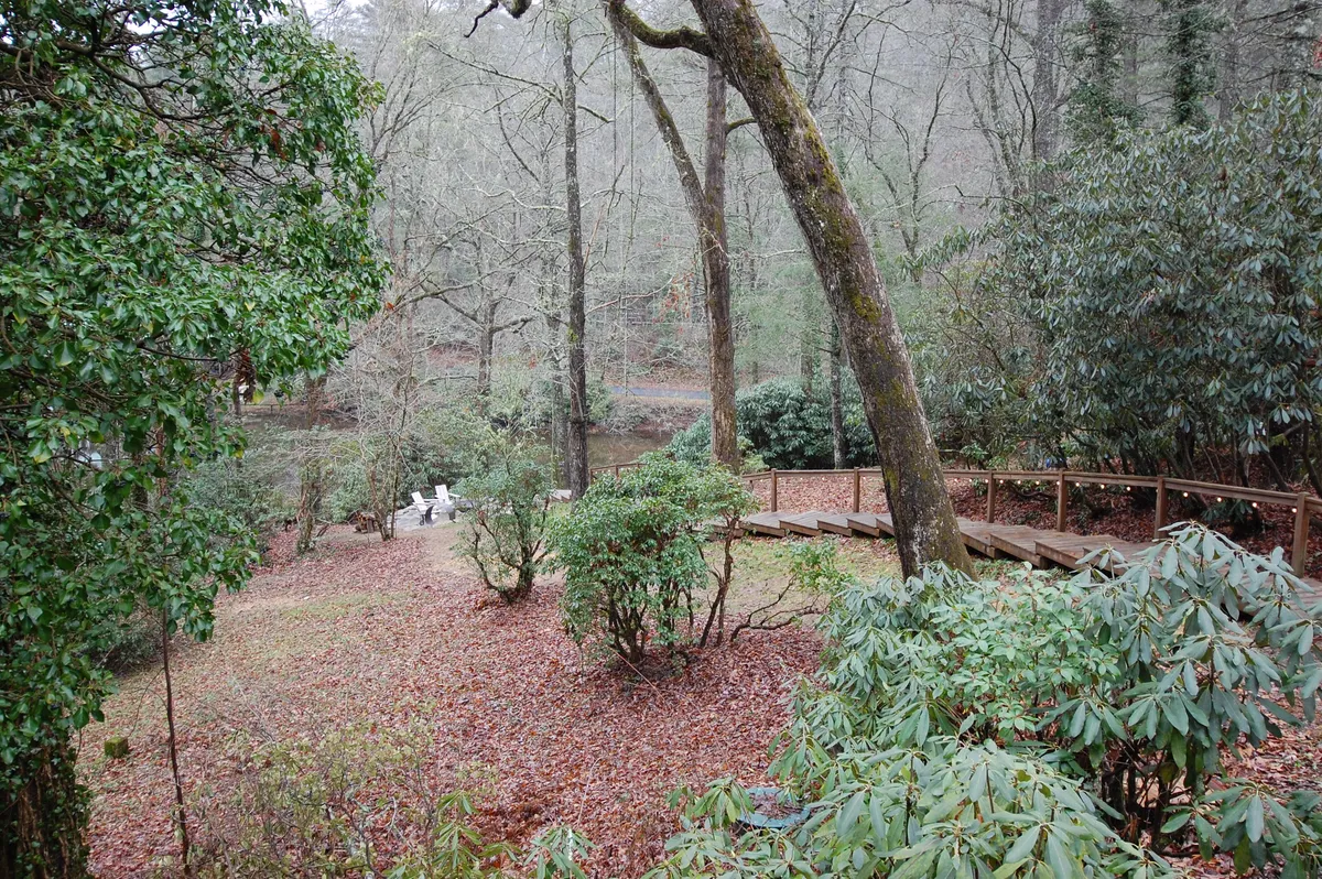 A scenic wooden walkway leads through lush greenery towards calm water in the background. The natural setting suggests opportunities for nature walks, birdwatching, or quiet moments by the lake, adding a sense of adventure and tranquility to the overall presentation.